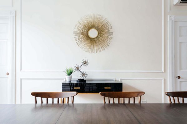 Dining room with wooden chairs, black console table and gold starburst mirror