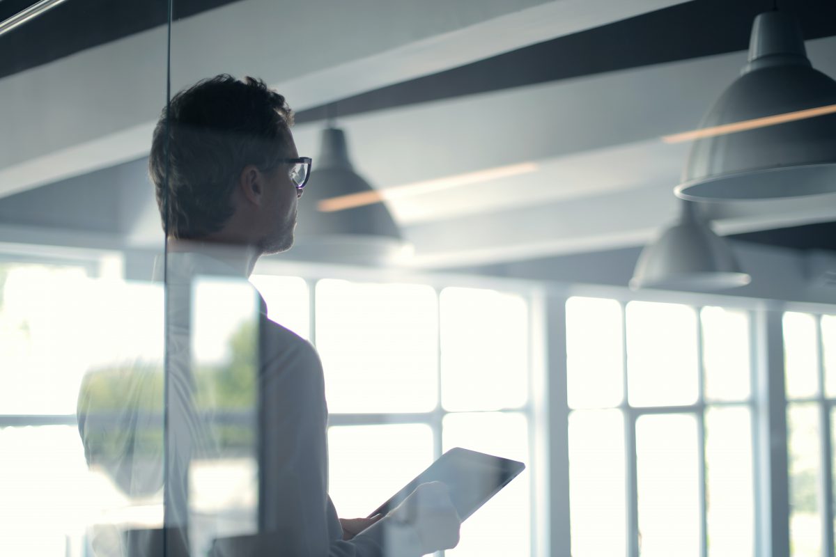 A man holding a tablet gives a presentation in an open office.