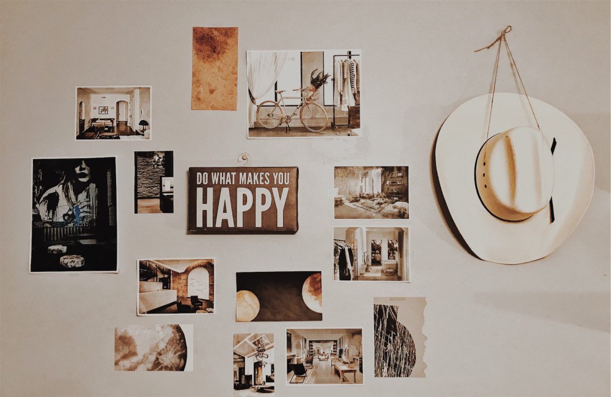 A wall featuring lots of small pieces of artwork and a hat, all in the tan color scheme.