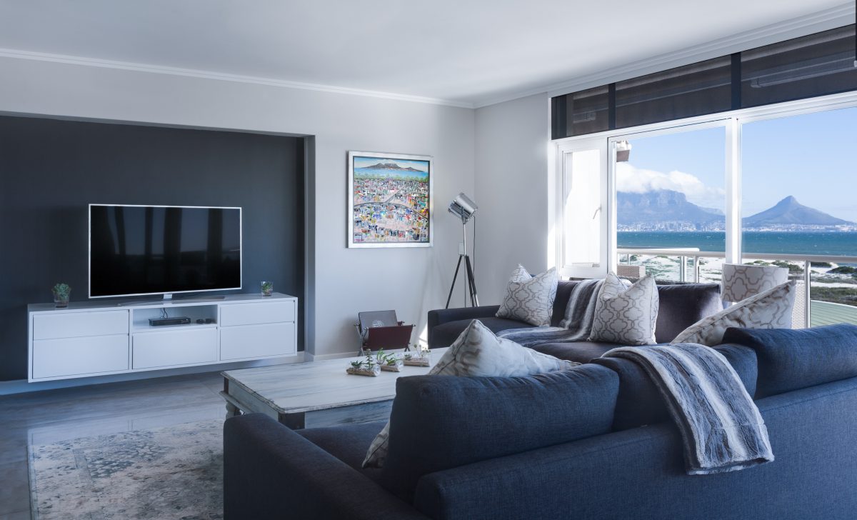 a clean and minimalist living room with inset TV, rug, coffee table, and dark couch with cream throw cushions