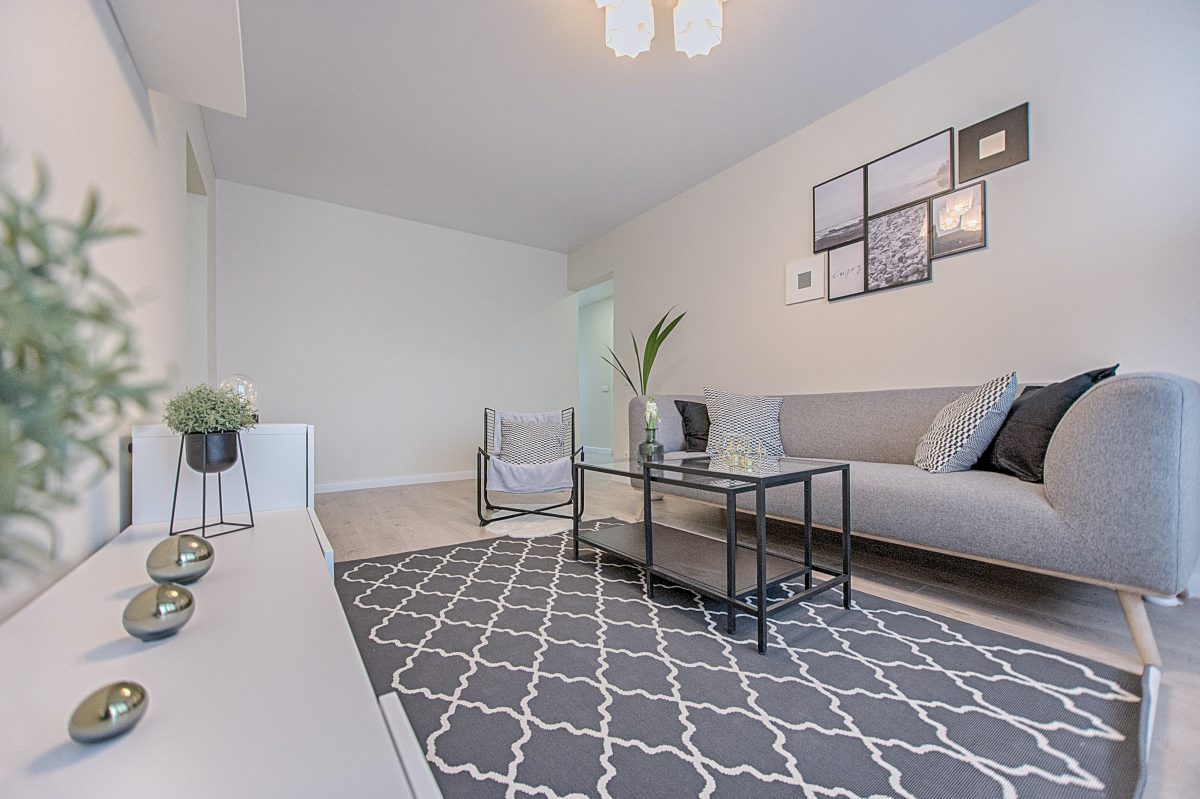 A small living room with a light gray color scheme and minimal furnishings.