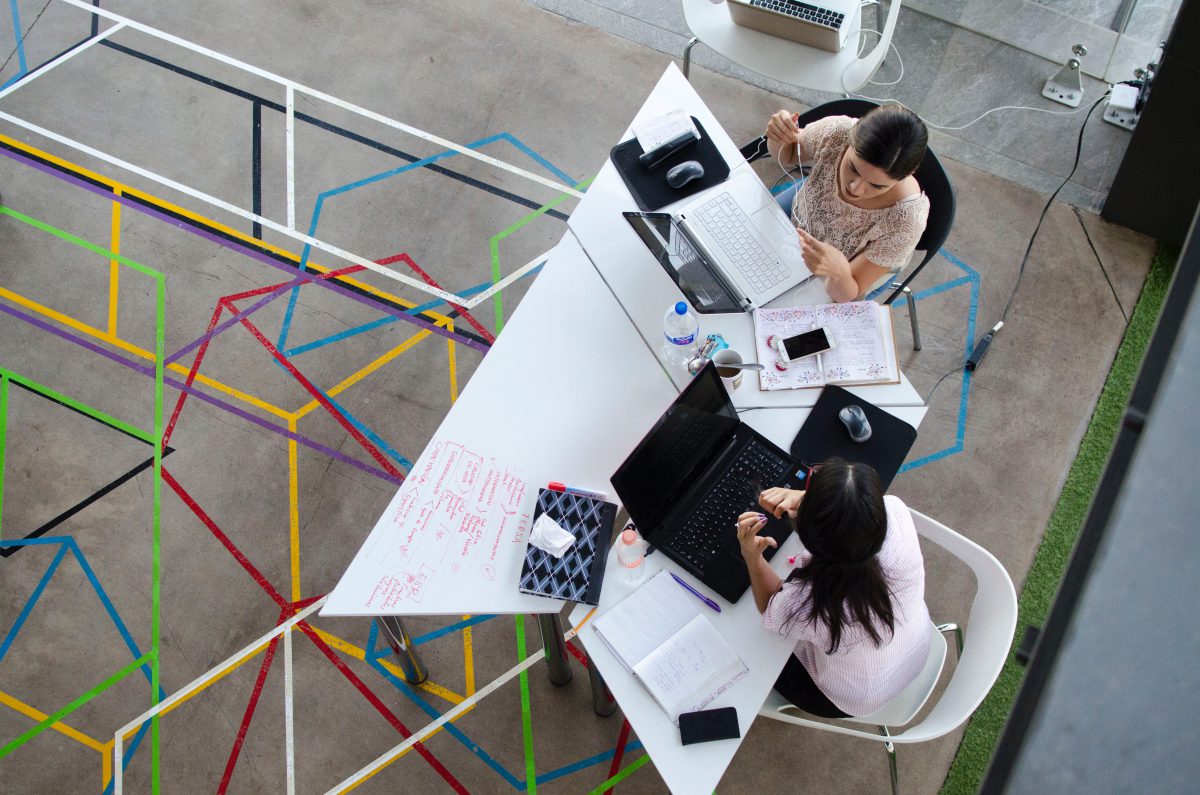 two women sitting in chairs using laptop computers photographed from above